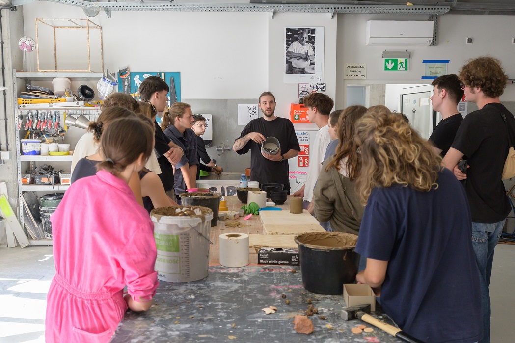 Students stand around a large work table in the ceramics studio.