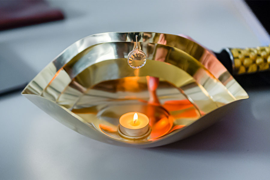 Metal ritual bowl in the shape of a semicircle with a lighted candle in the center.