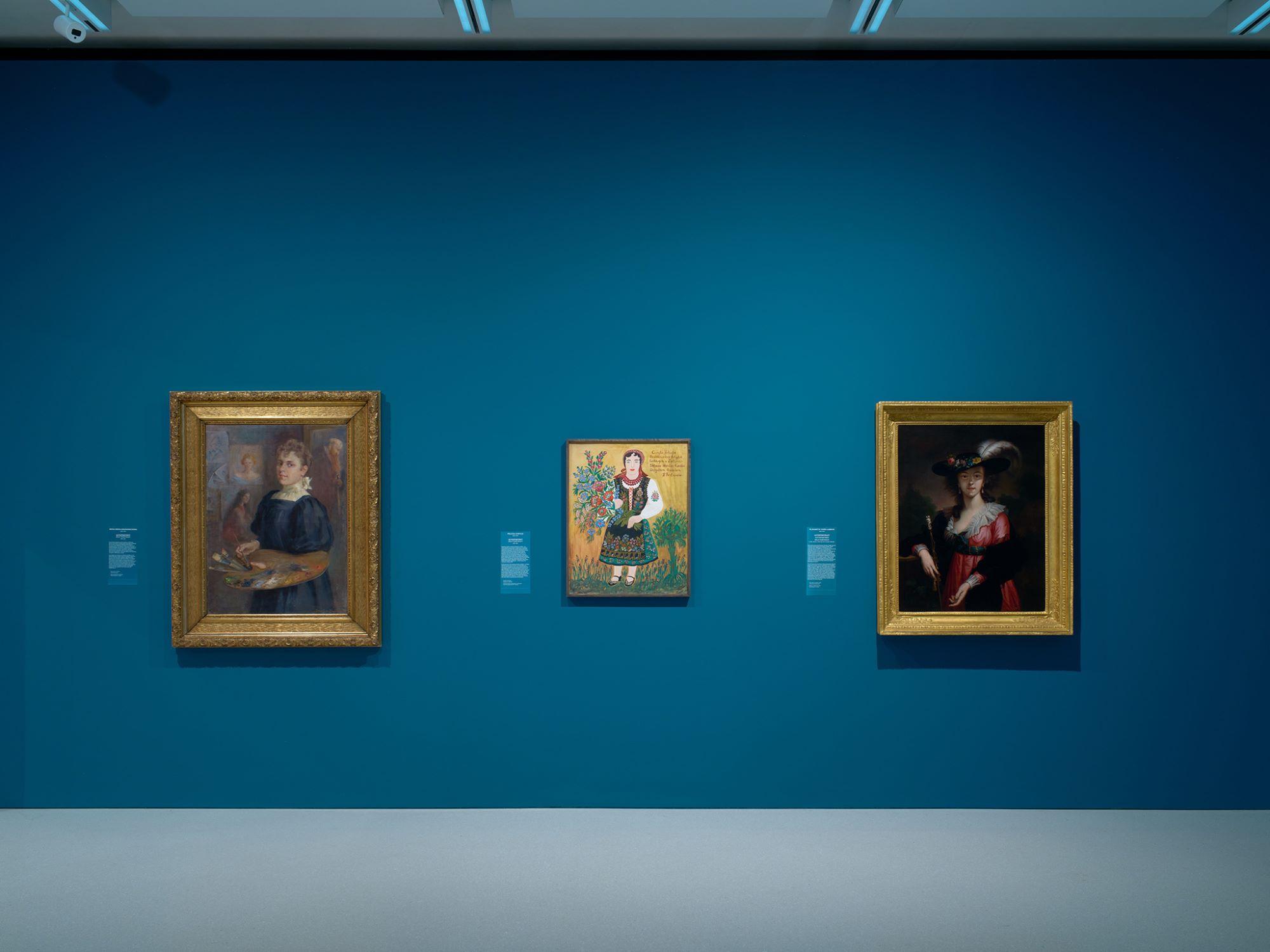 Three paintings hanging on a wall in the museum