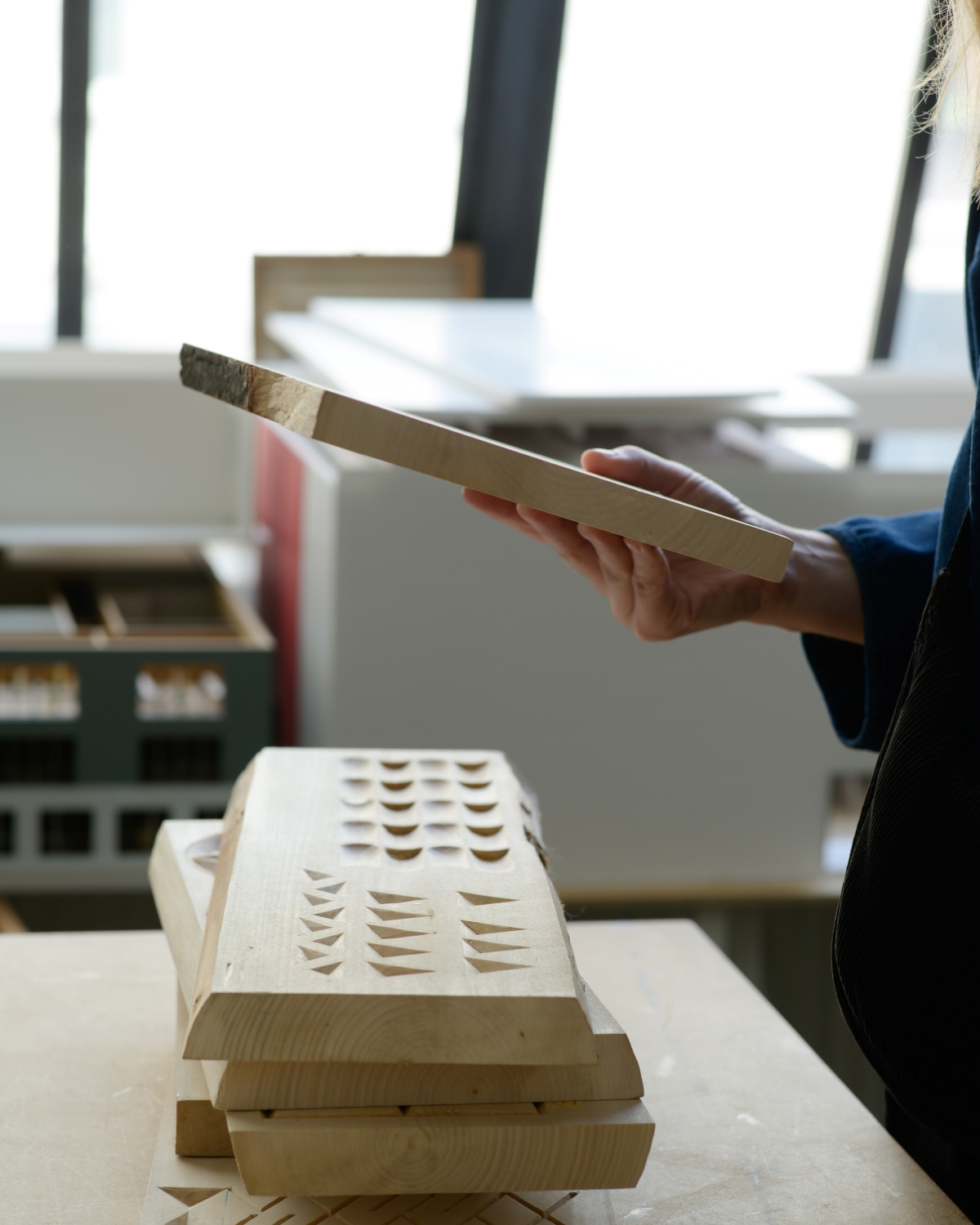 Stack of wooden tiles with cut-out patterns; a hand holds one of them