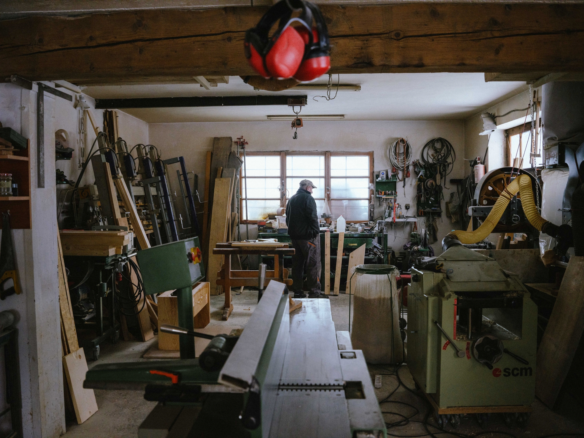 View of a craftsman’s workshop; the craftsman stands at the far end by the window, waiting for something
