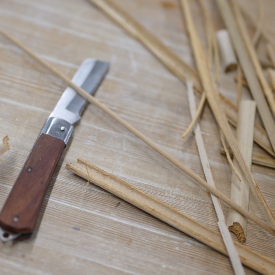 Close-up of the knife and pieces of bulrush lying on the table