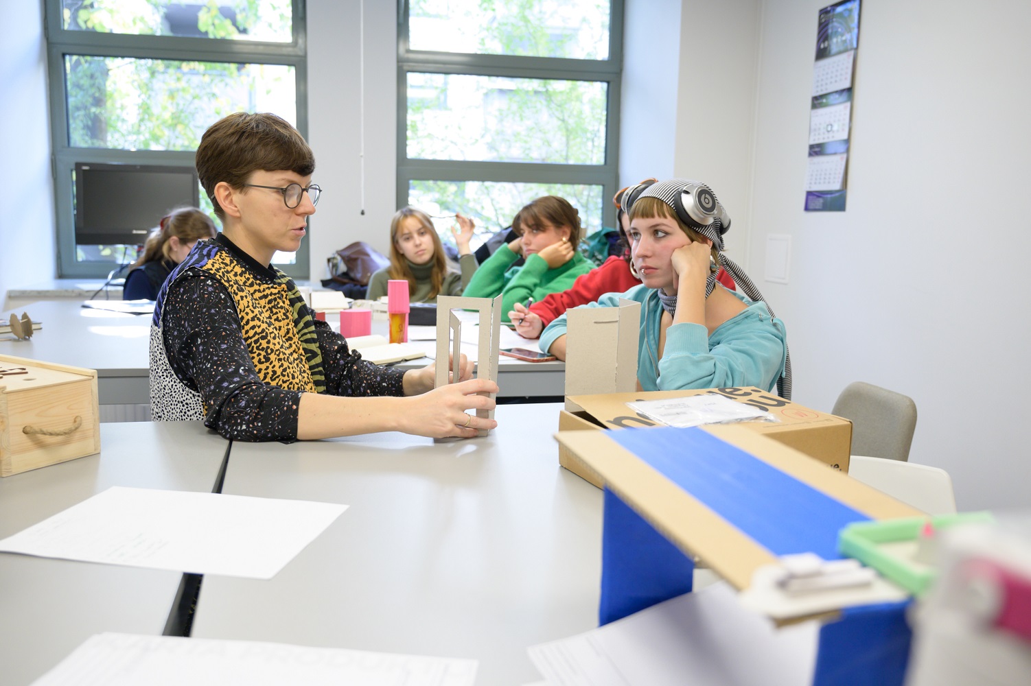 Prowadząca zajęcia omawia ze studentką makietę wykonaną z tektury.