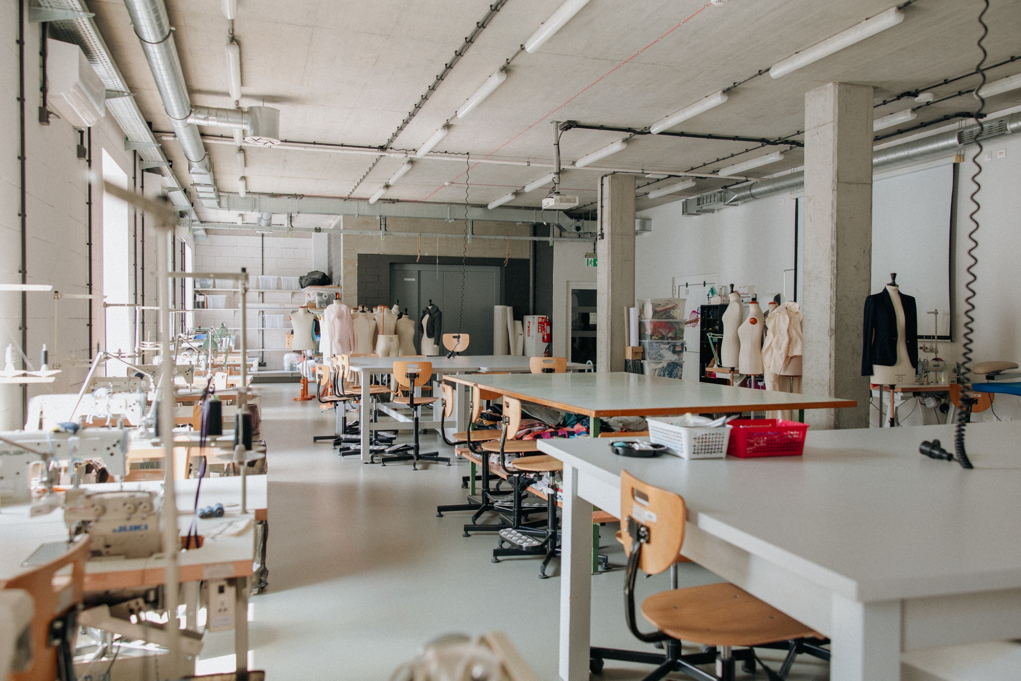 Interior of the Sewing Workshop, with worktables on the right and sewing machines on the left.