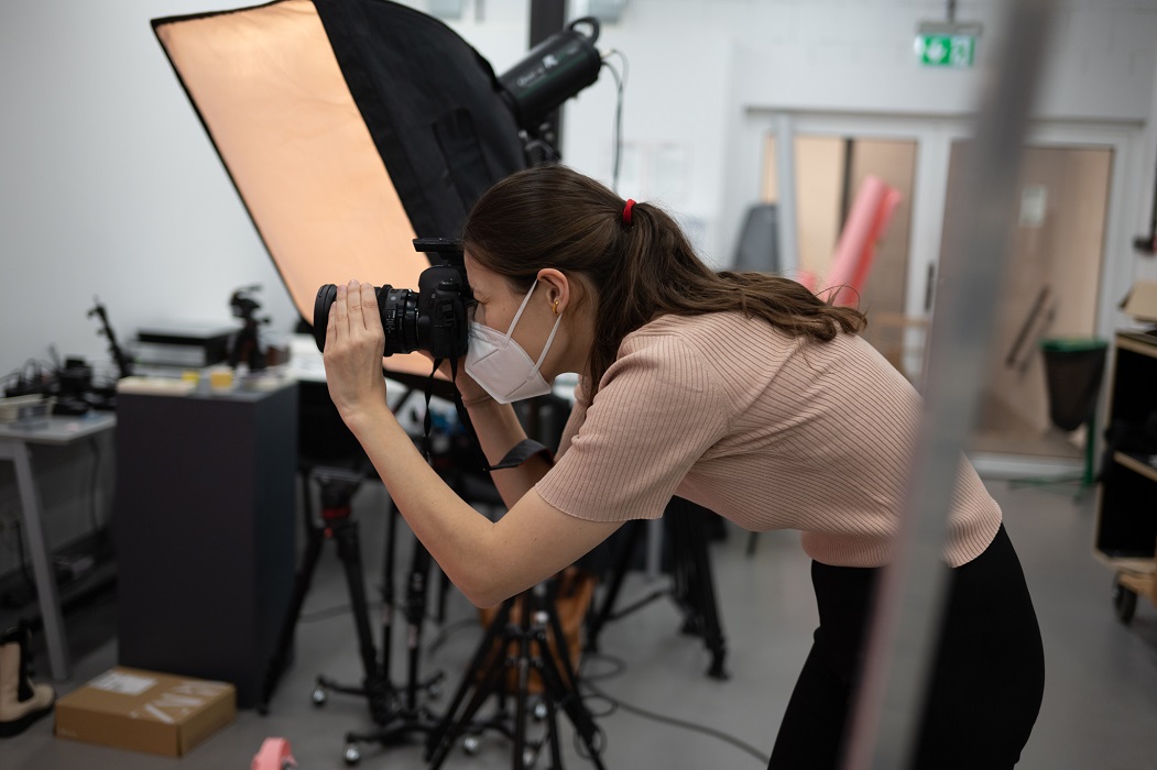 A woman in a mask takes a picture in a photo studio.