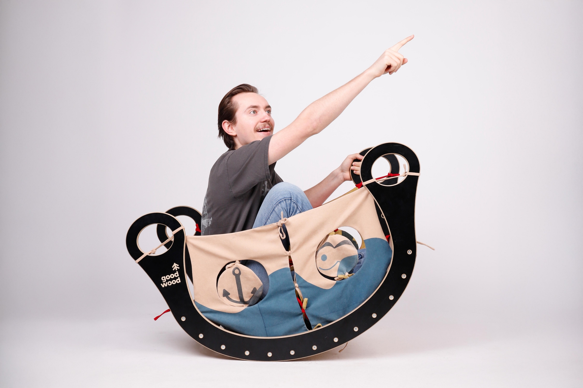 Rocker with accessories that turn it into a boat; a young man is sitting inside, pointing the way forward.