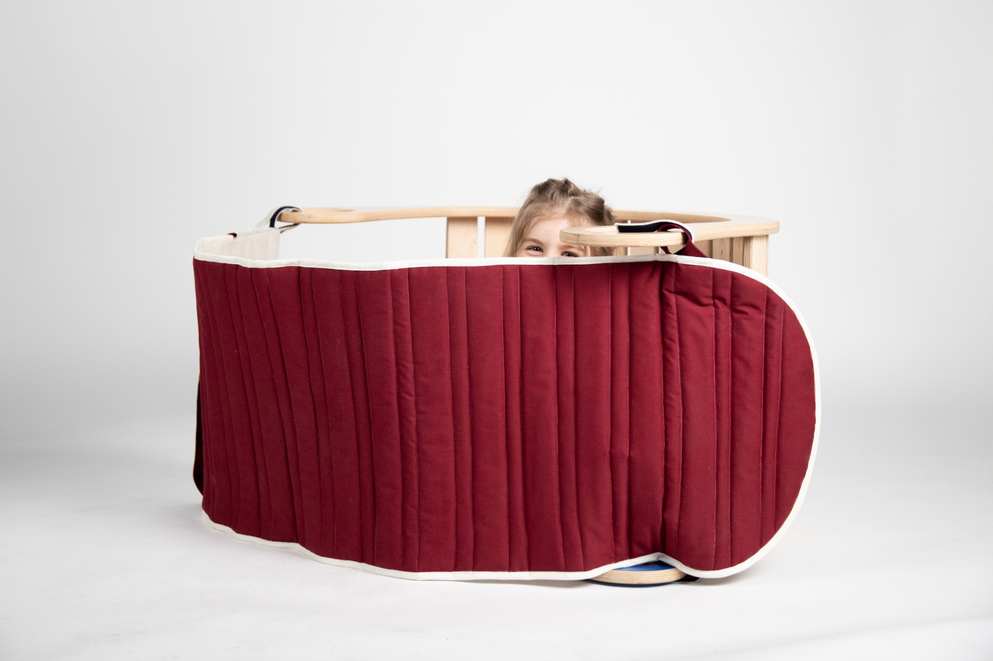 Rocker with accessories that turn it into a hideaway; the top of a small child’s head peeks out from behind the mat.