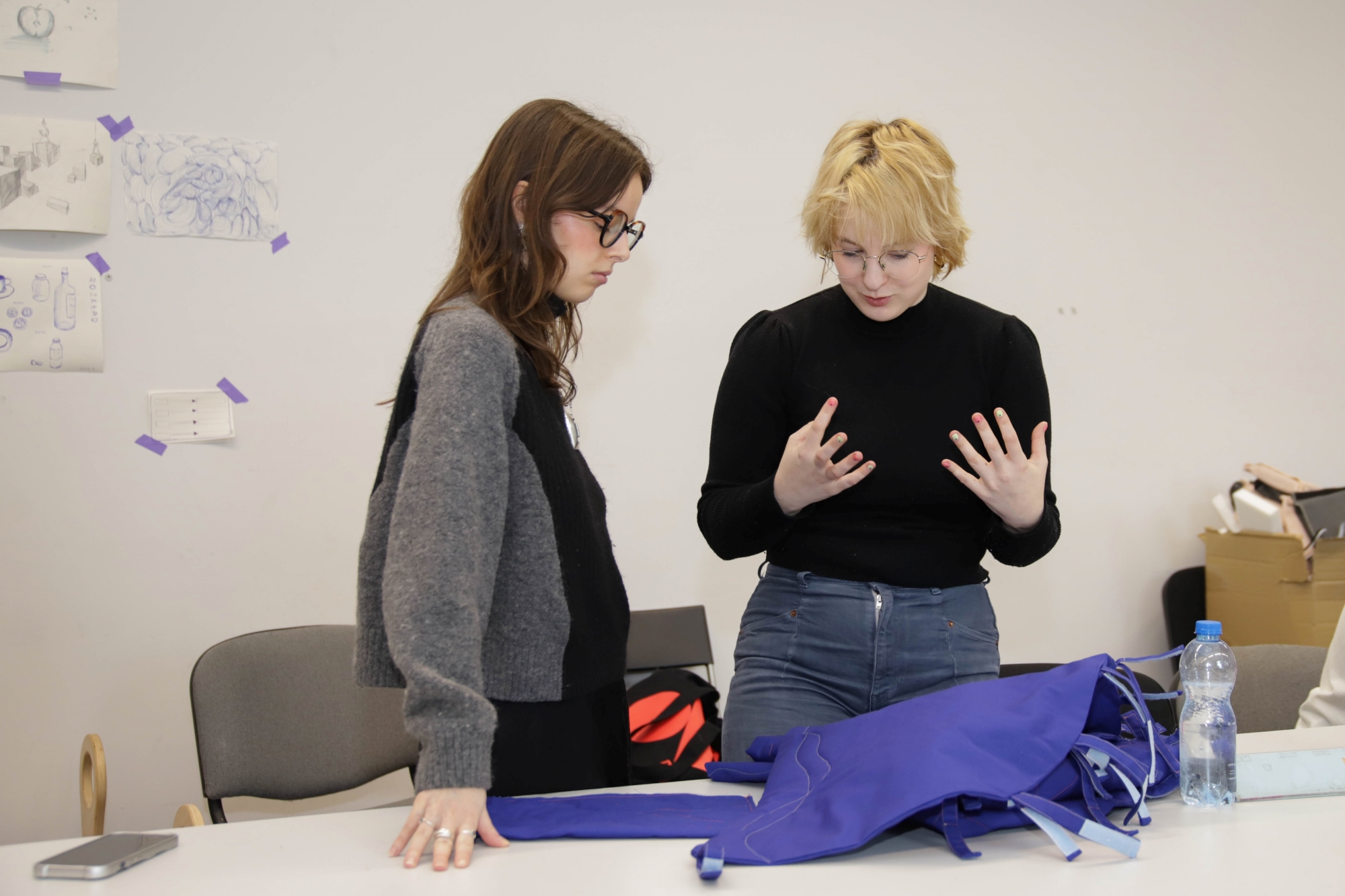 Two students discussing their project, with materials spread out on the table in front of them.