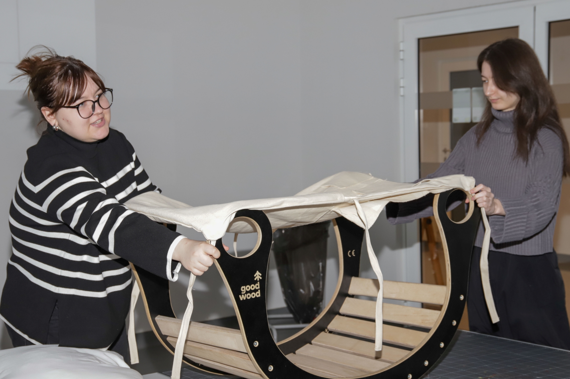 Two students pulling fabric tightly over a rocker.
