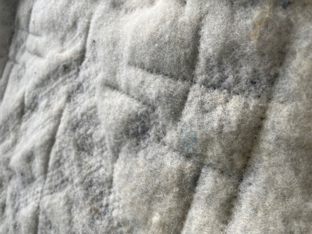 Close-up of a charcoal wool felt panel with machine-made, raised lines forming a ribbed texture.