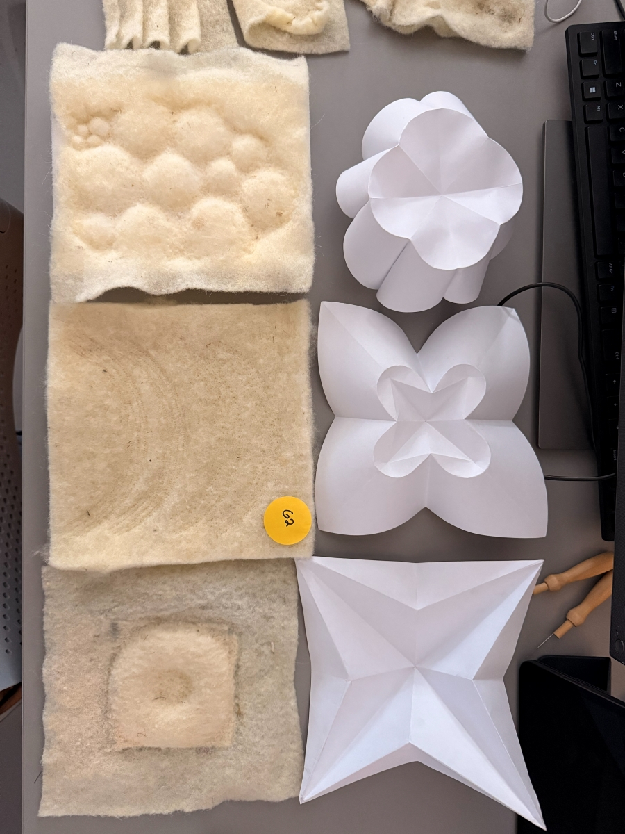 Close-up of felt pieces with various raised textures arranged next to paper origami structures.