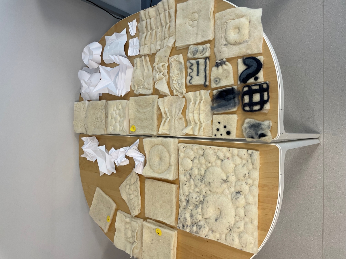 A collection of several felt samples with different textures, densities, and three-dimensional patterns laid out next to each other.